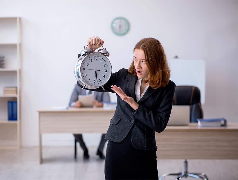 Auszubildende zeigt schockiert auf eine Uhr