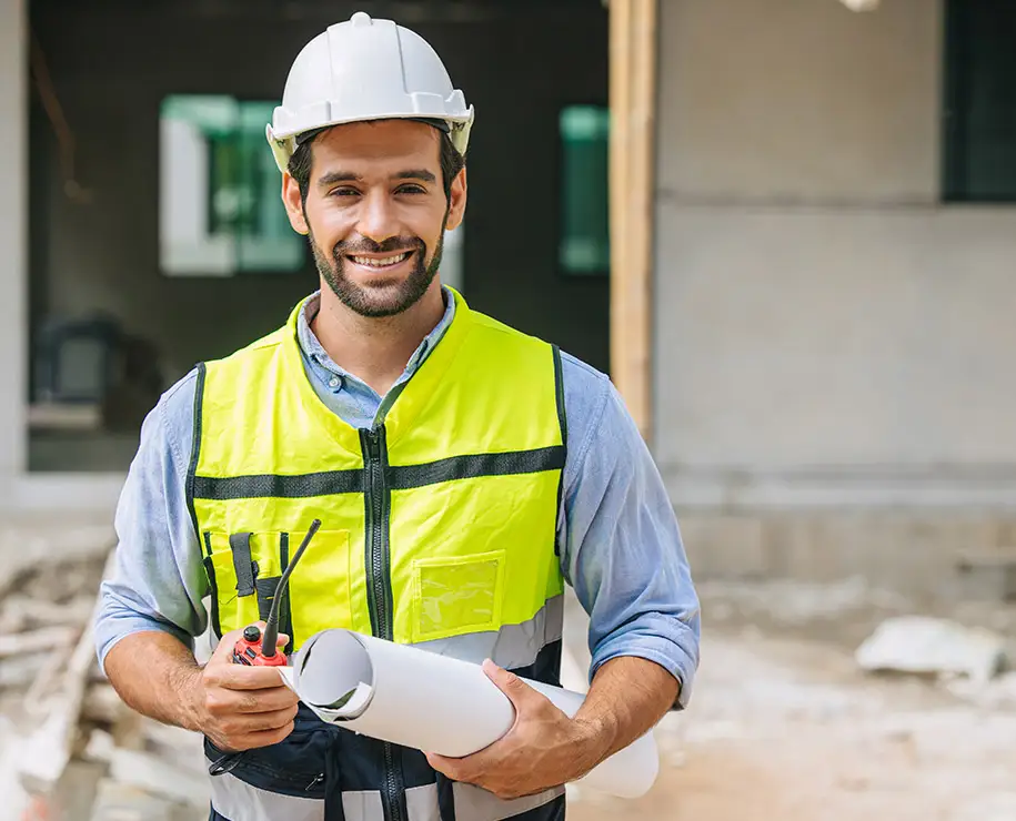 Ein freundlicher Bauarbeiter lächelt für die Kamera auf einer Baustelle